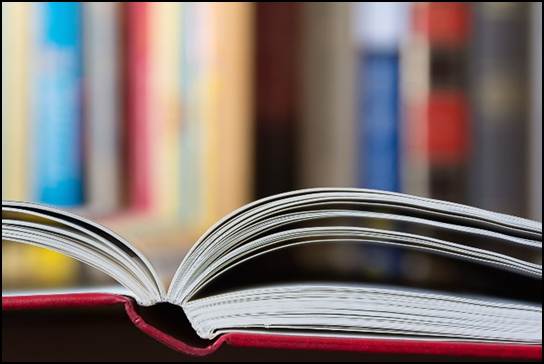 Close-up of open book against blurred bookshelf background